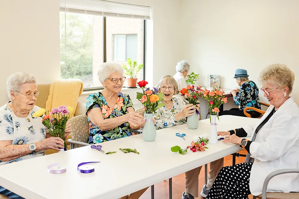 Residents enjoying a flower-arranging activity together at a table.