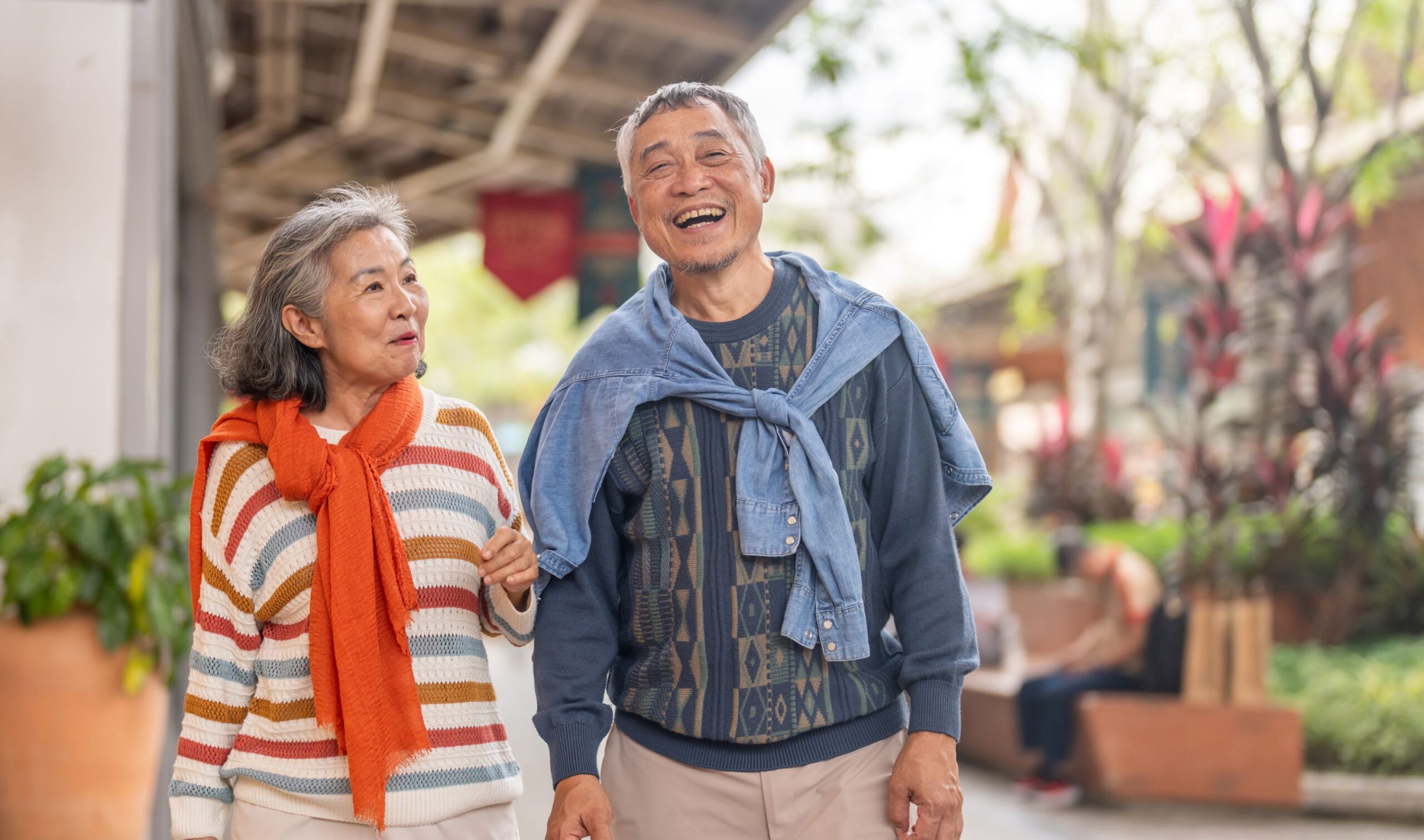 Senior couple walking arm-in-arm and smiling outdoors